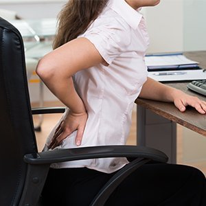 mujer con dolor de espalda de estar sentada