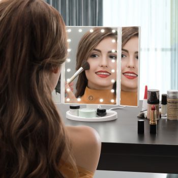 mujer maquillandose delante de un espejo con luz